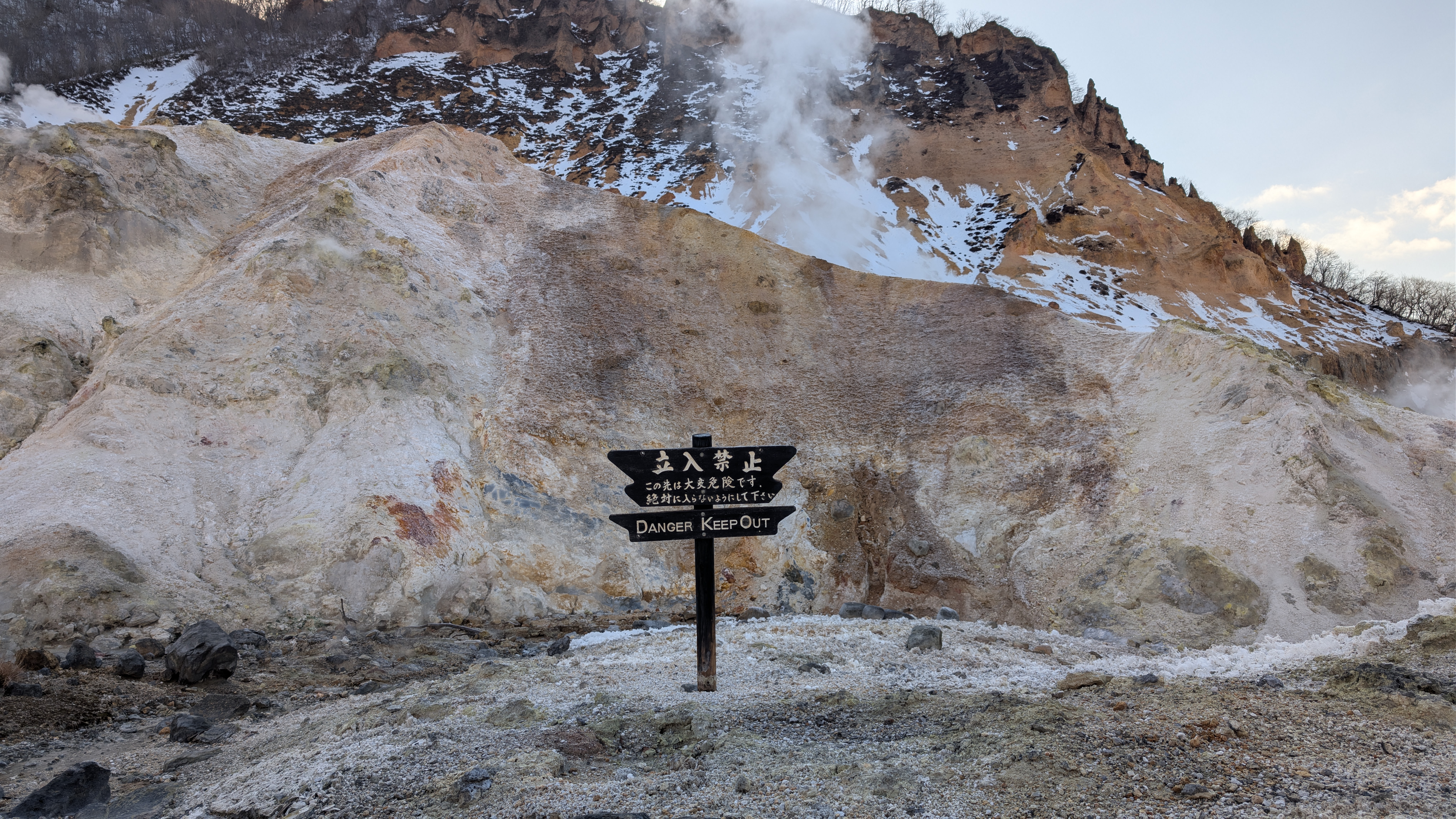 Ein Warnschild im Jigokudani warnt vor den vulkanischen Gasen und der extremen Hitze des Bodens.