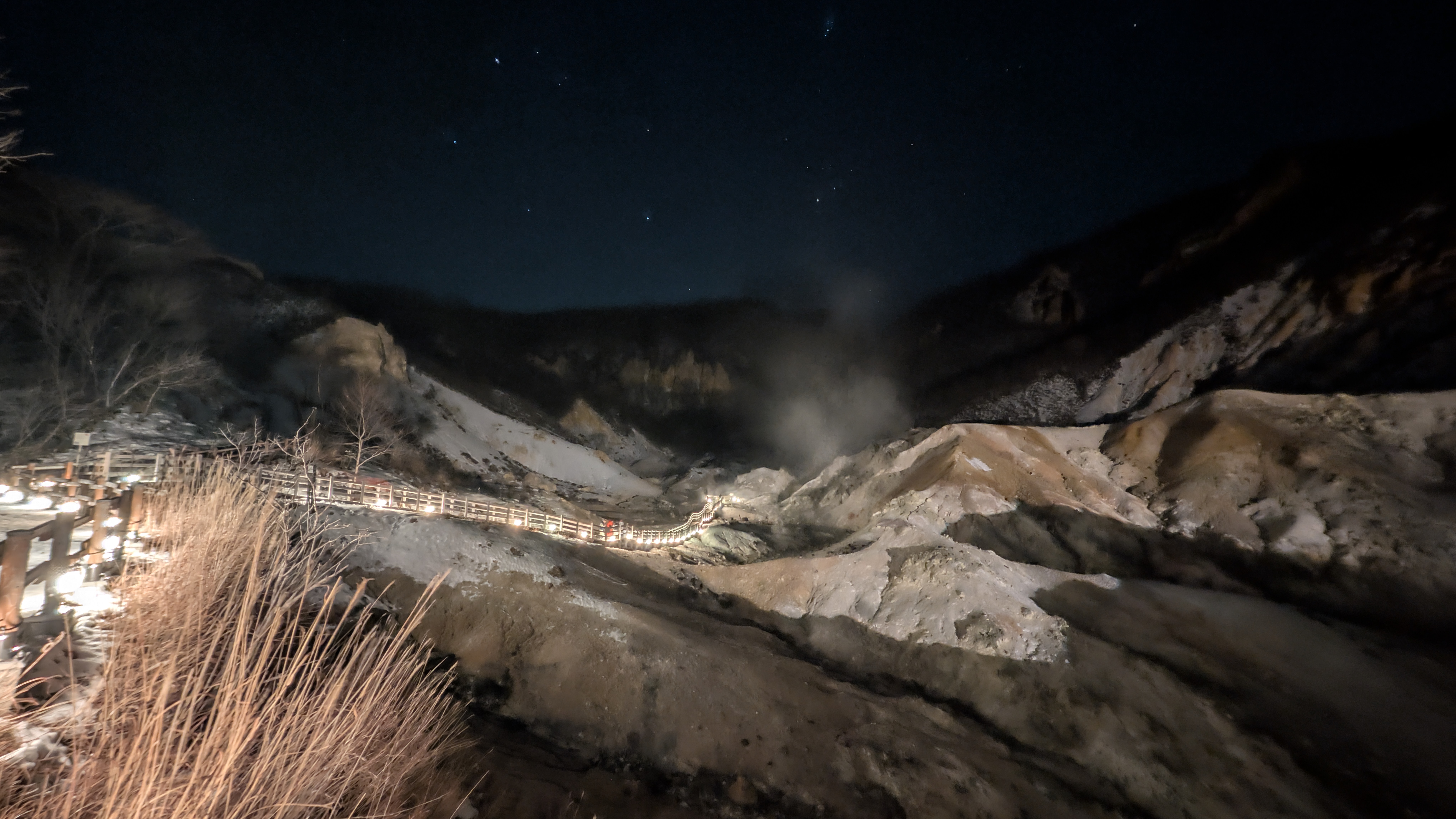 Der beleuchtete Holzweg durch das dampfende Höllental bei Nacht.