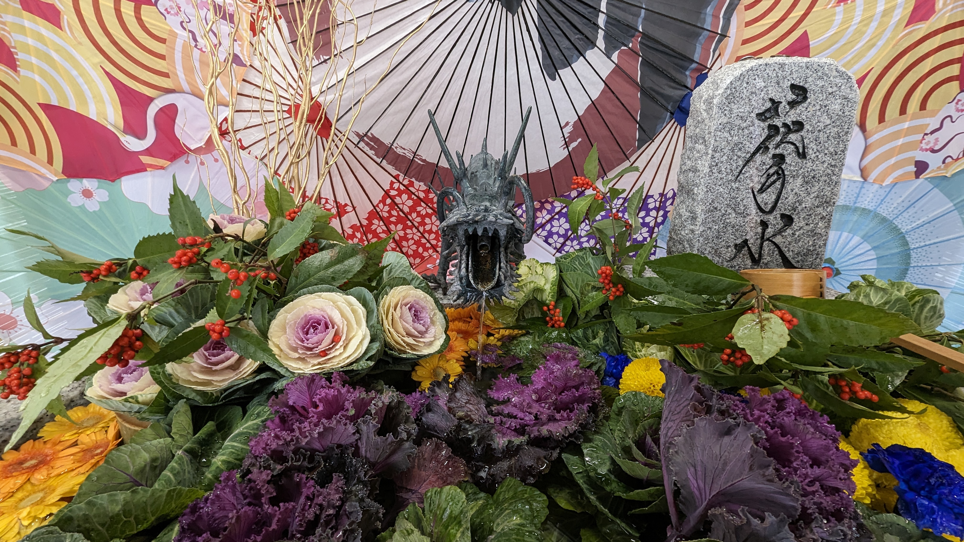 Blumen, Regenschirme und eine Statue eines Drachen